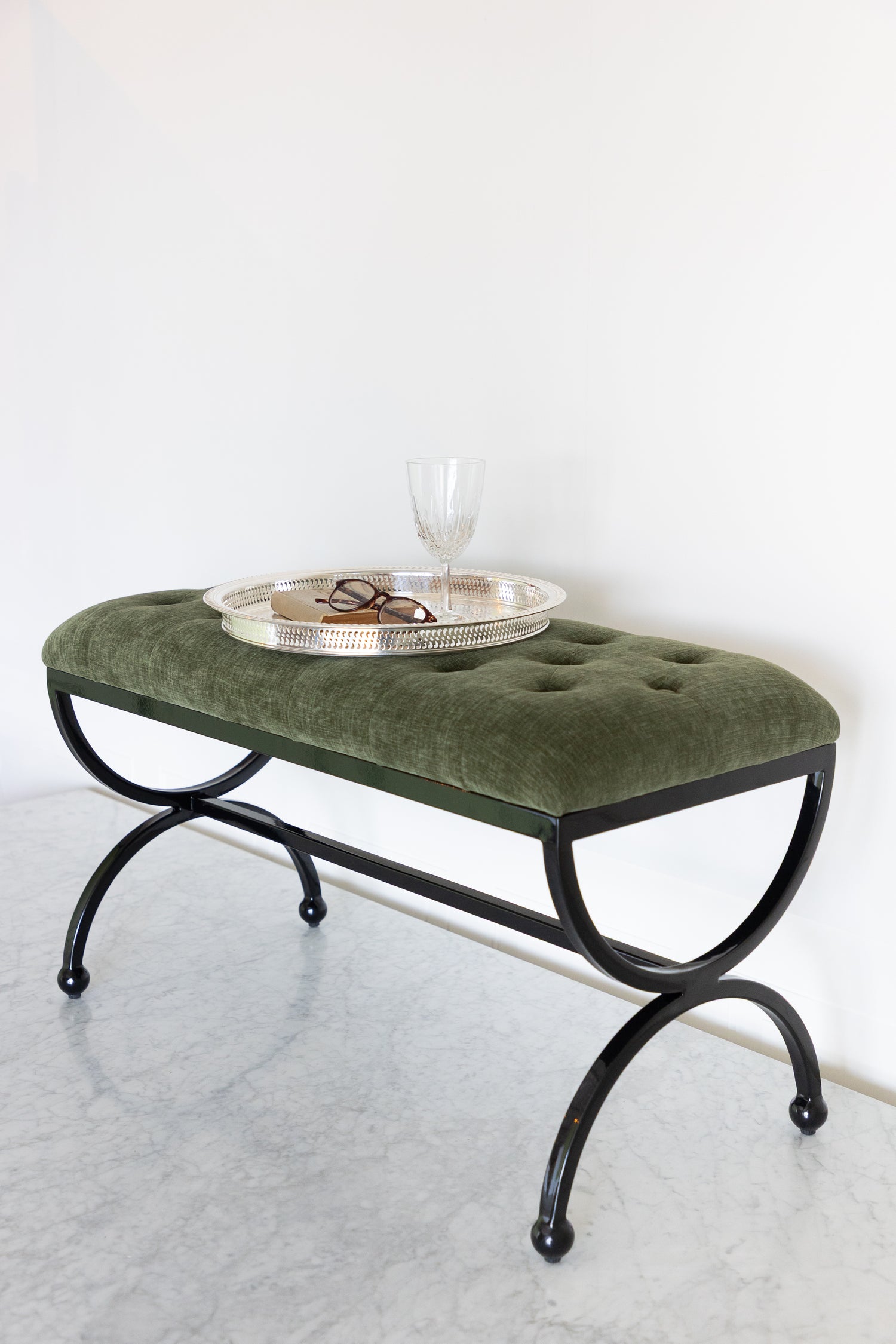 Green upholstered bench with a round metal tray on a white background