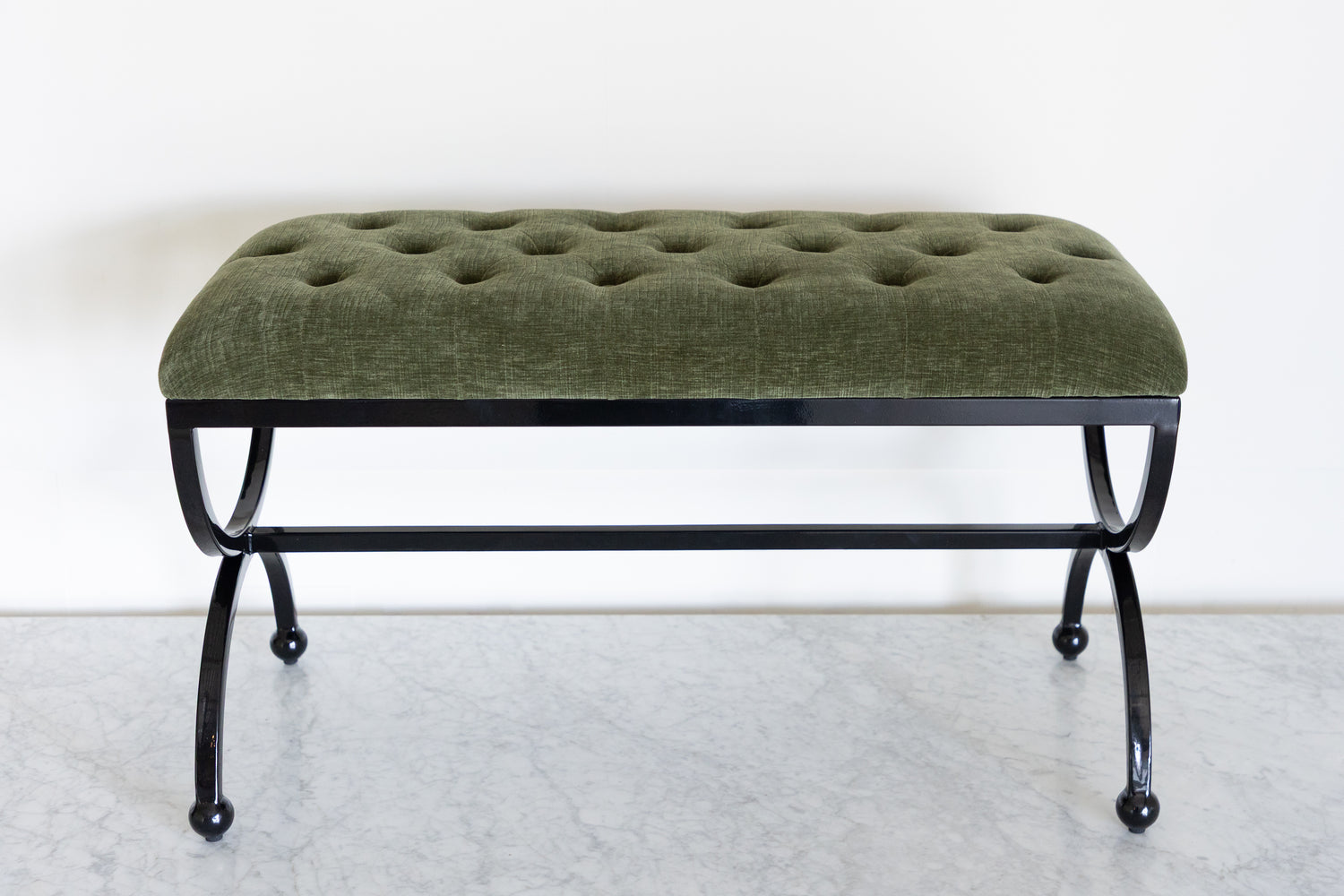 Green upholstered bench with black metal frame on a white background