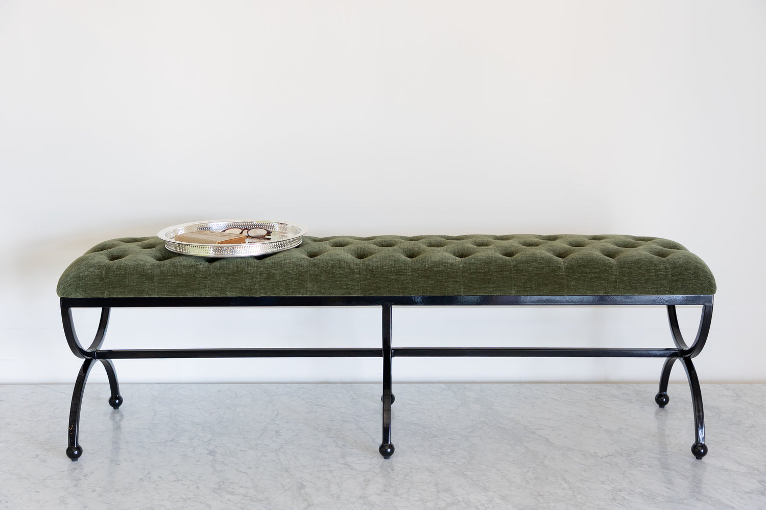Green upholstered bench with a round metal tray on a white background