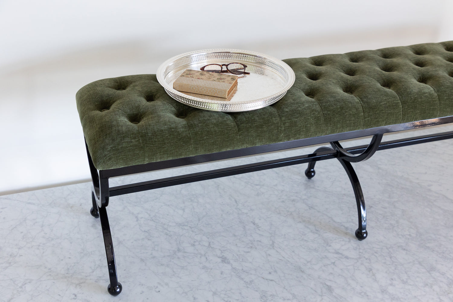 Green upholstered bench with a round metal tray on a white background