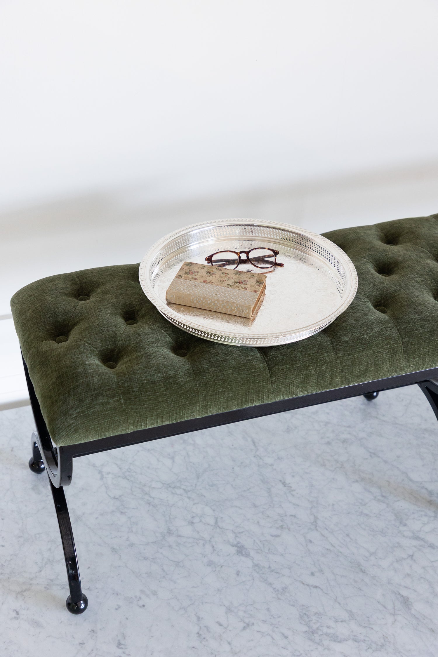Green upholstered bench with a round metal tray on a white background