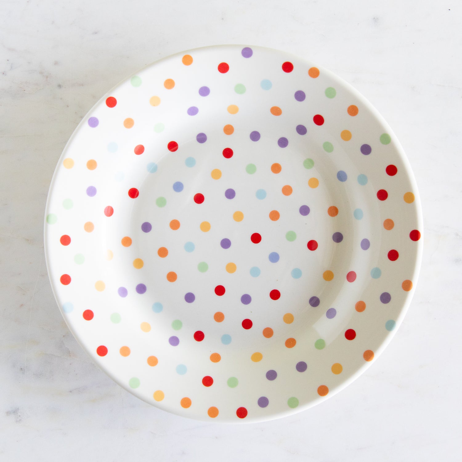 Polka dot plate with colorful spots on a white background.