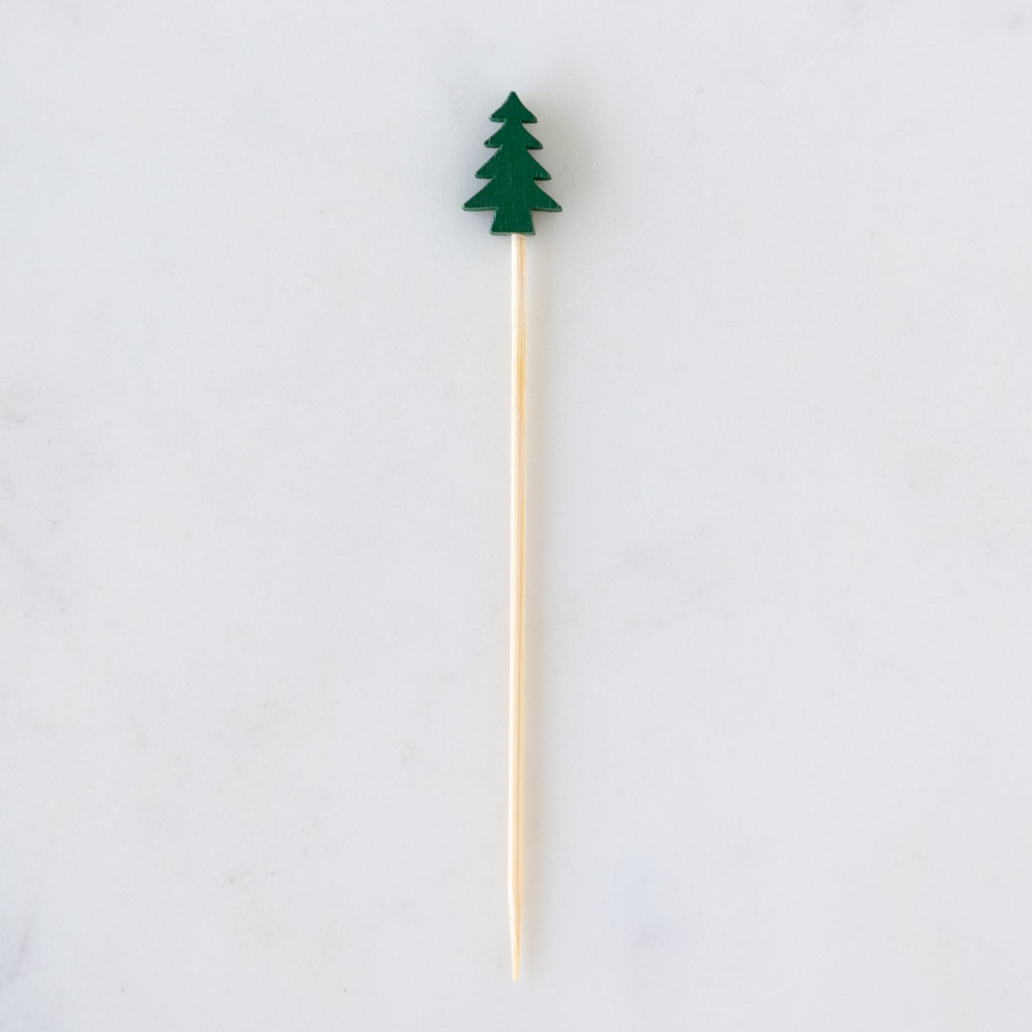 Wooden skewer with a green tree-shaped top on a white background.