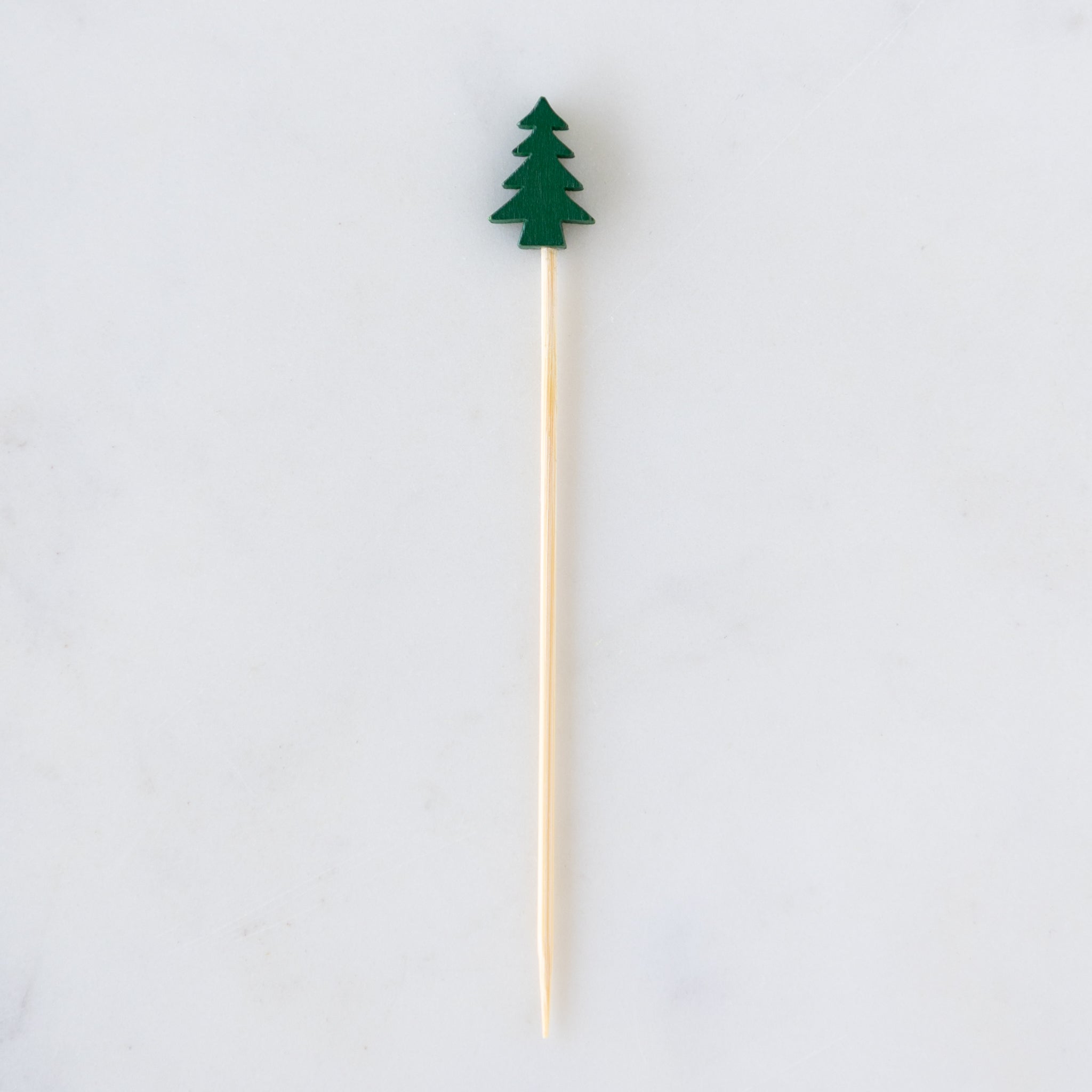 Wooden skewer with a green tree-shaped top on a white background.