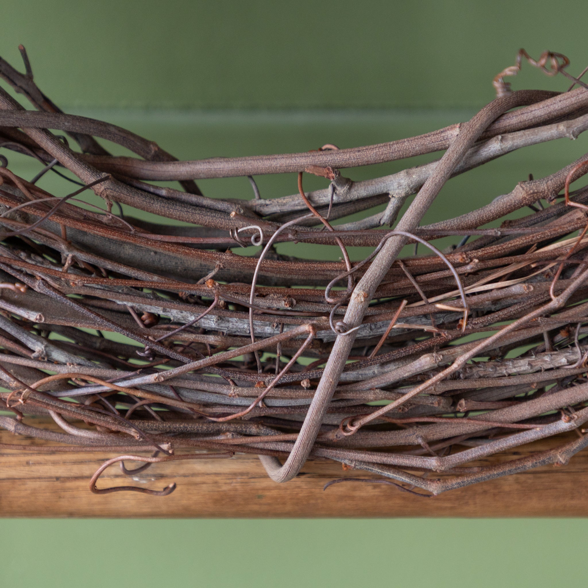 Close-up of a wreath made of vines on a green background.