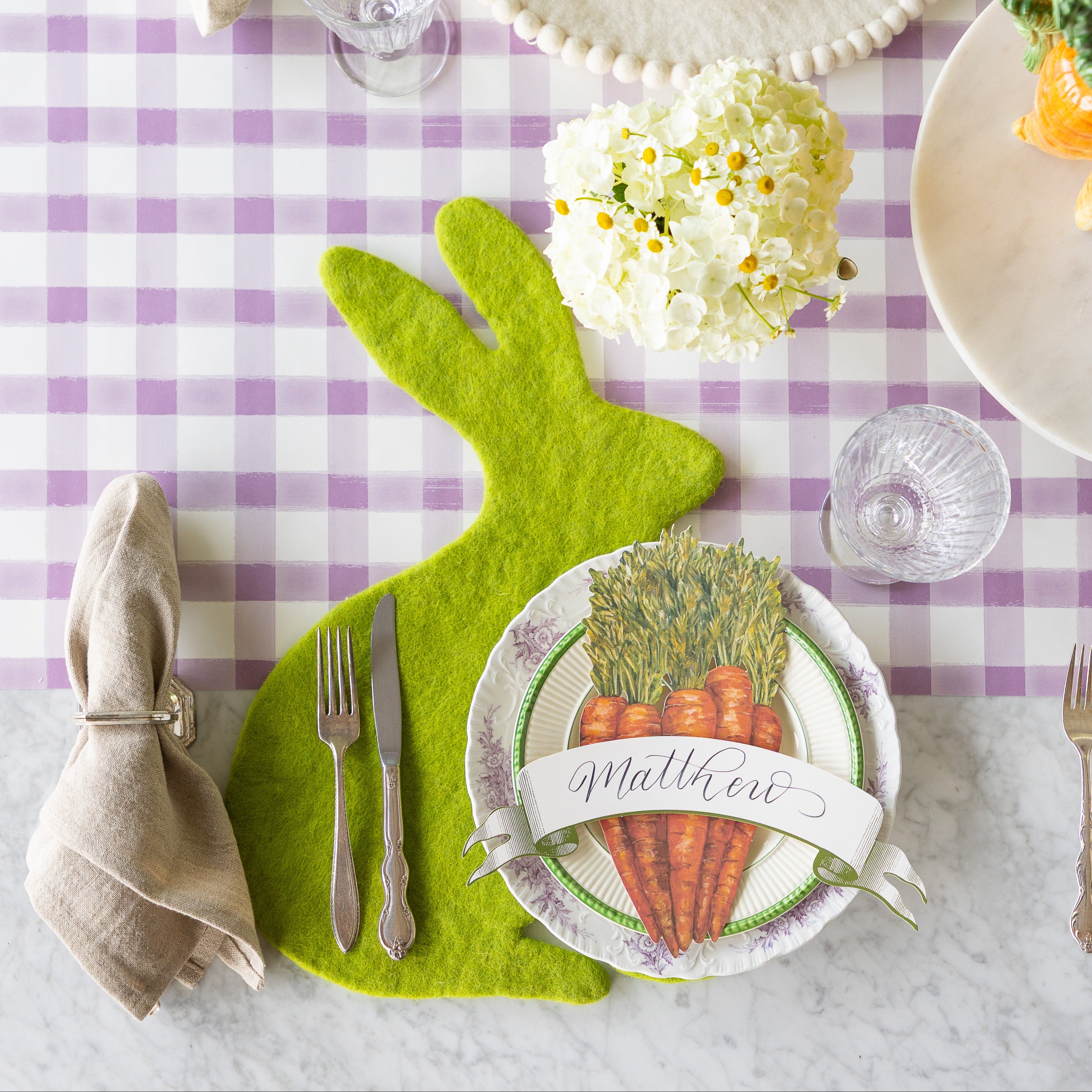 Easter table setting with the Spring Green Easter Bunny Placemat, Carrots and Classic Moss Banner Table Accents, vintage dinnerware and flowers on the Lilac Painted Check.