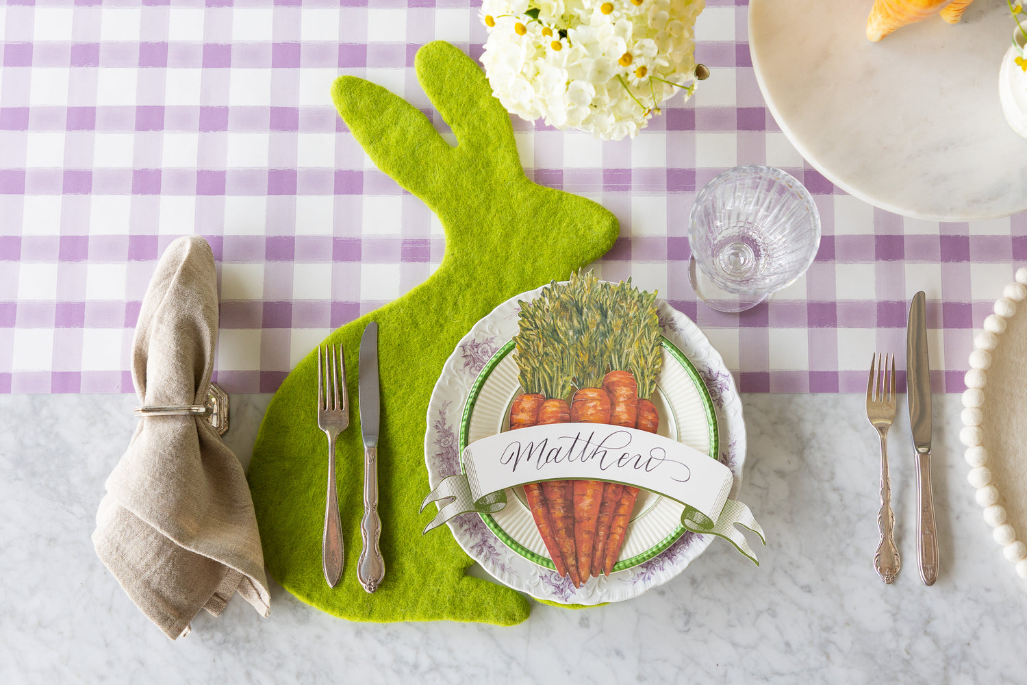 Easter themed table setting featuring the Spring Green Bunny Felt Placemat, Carrots and Moss Green Banner Table Accents on the Lilac Painted Check Runner.