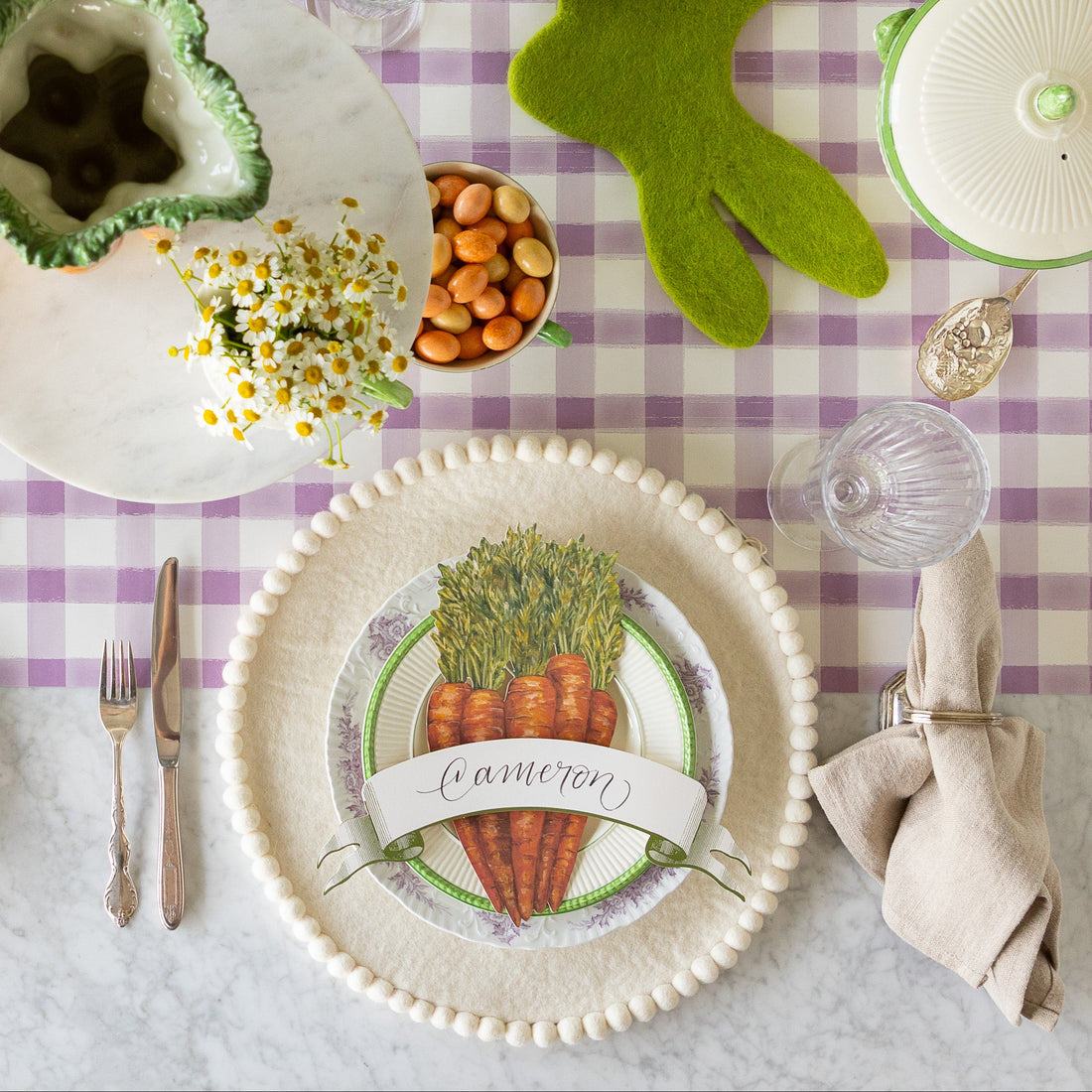Easter table setting with the Ivory Felt Pom Pom Placemat, decorative plates, Carrots &amp; Moss Classic Banner Table Accents on the Lilac Painted Check Runner.