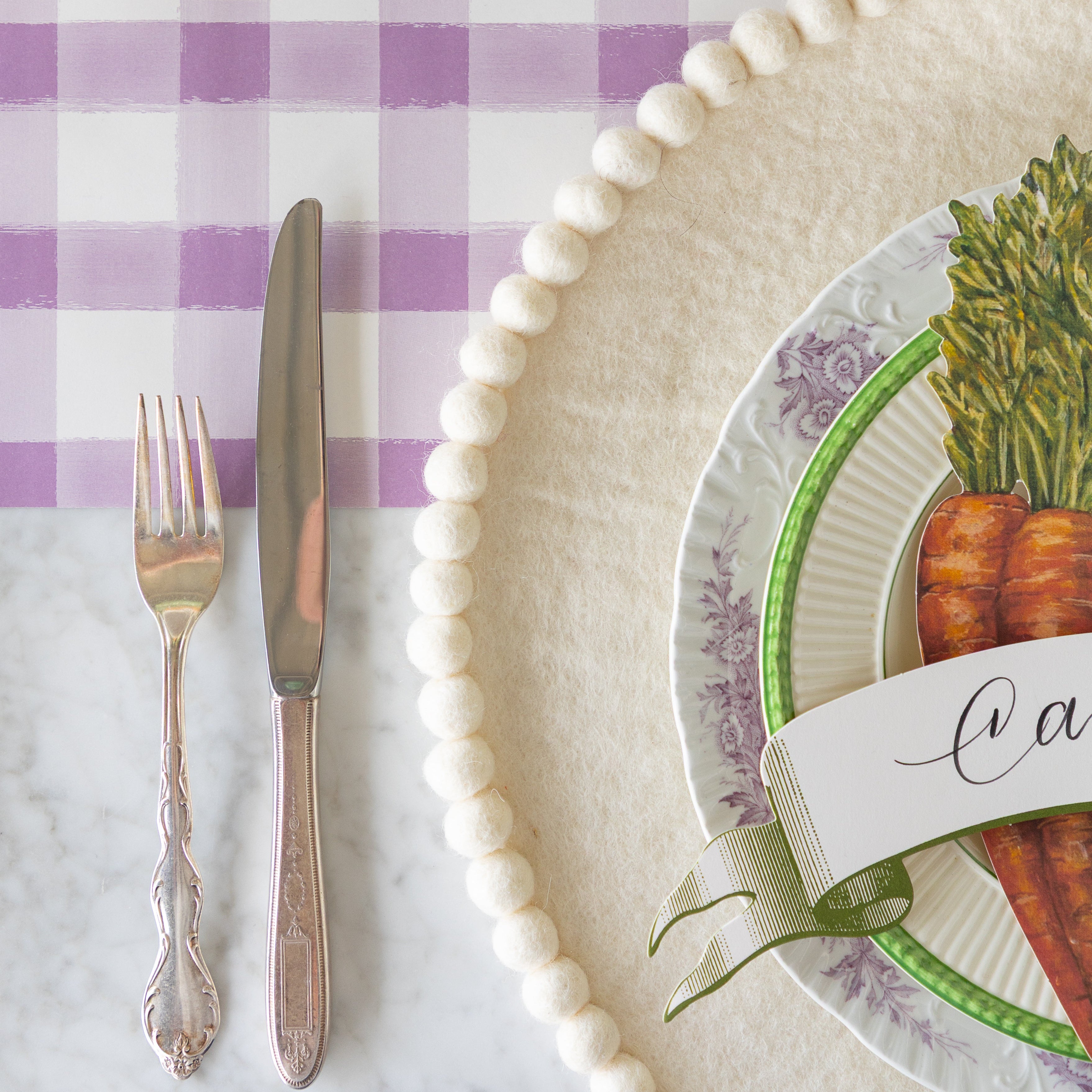 A close up of the Ivory Pom Pom Felt Placemat under a place setting.