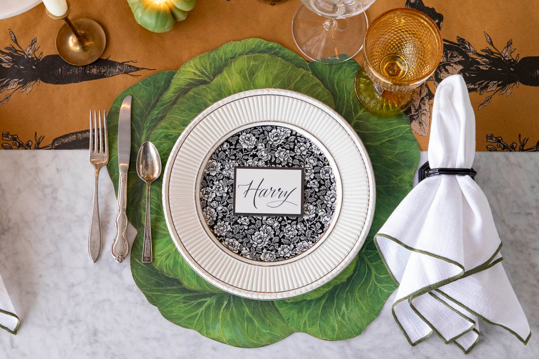 Dining table setting with a decorative plate, cutlery, and napkin on the Die-cut Cabbage Placemat and Farmers&