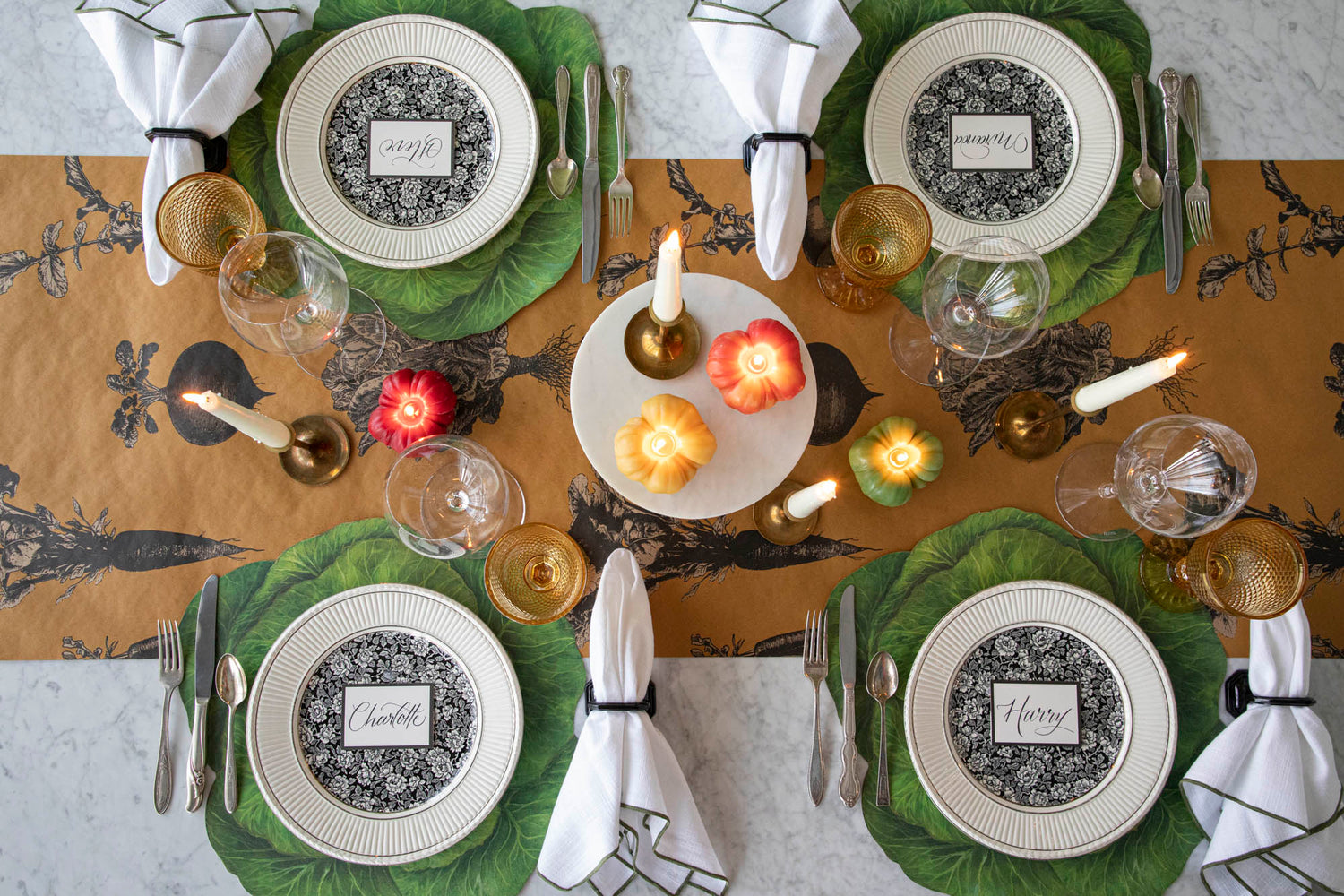 Dining table setting with decorative plates, cutlery, candles, and napkins on the Die-cut Cabbage Placemats and Farmers&