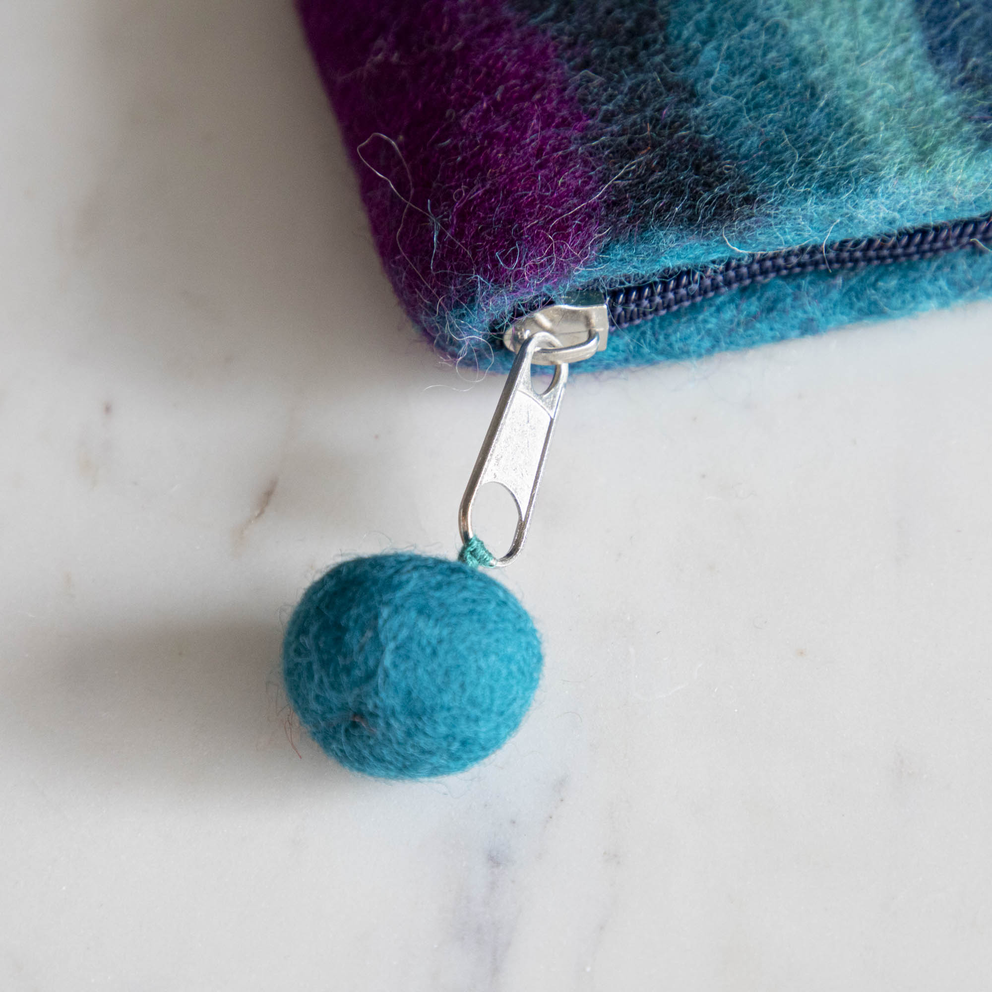 A close up of the Felt Rainbow Pouch with the felt pom at the end of the zipper pull.