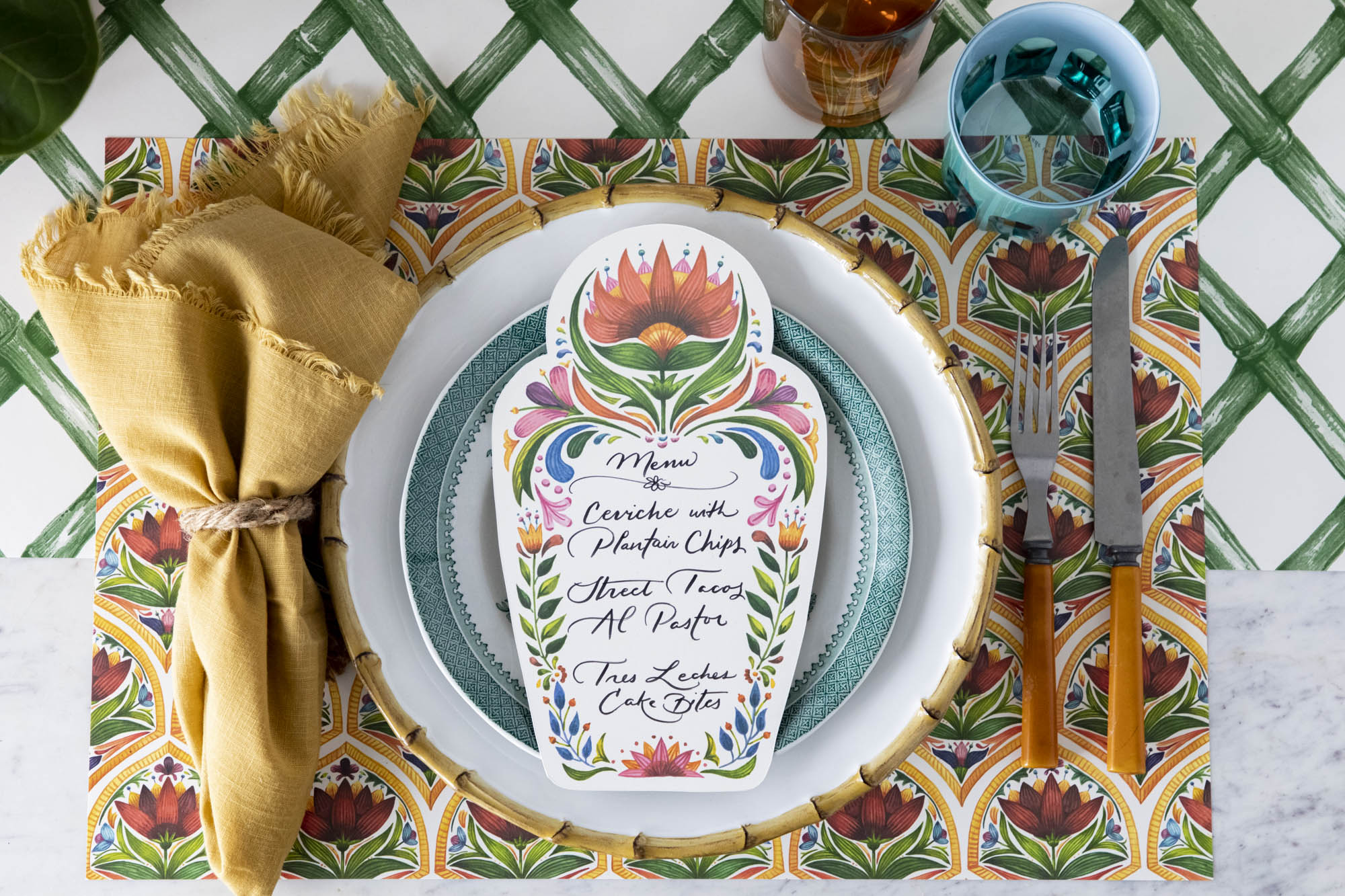 A vibrant place setting featuring a Fiesta Floral Table Card with a menu written on it in beautiful script resting on the plate, from above.