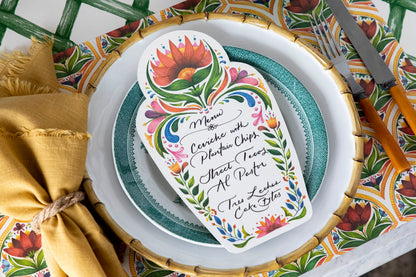 A vibrant place setting featuring a Fiesta Floral Table Card with a menu written on it in beautiful script resting on the plate.
