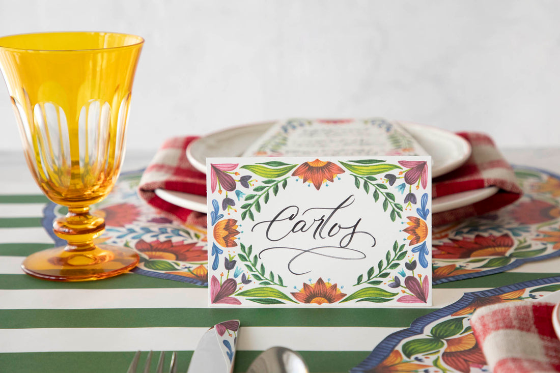 A Fiesta Floral Place Card labeled &quot;Carlos&quot; standing on a vibrant table setting.