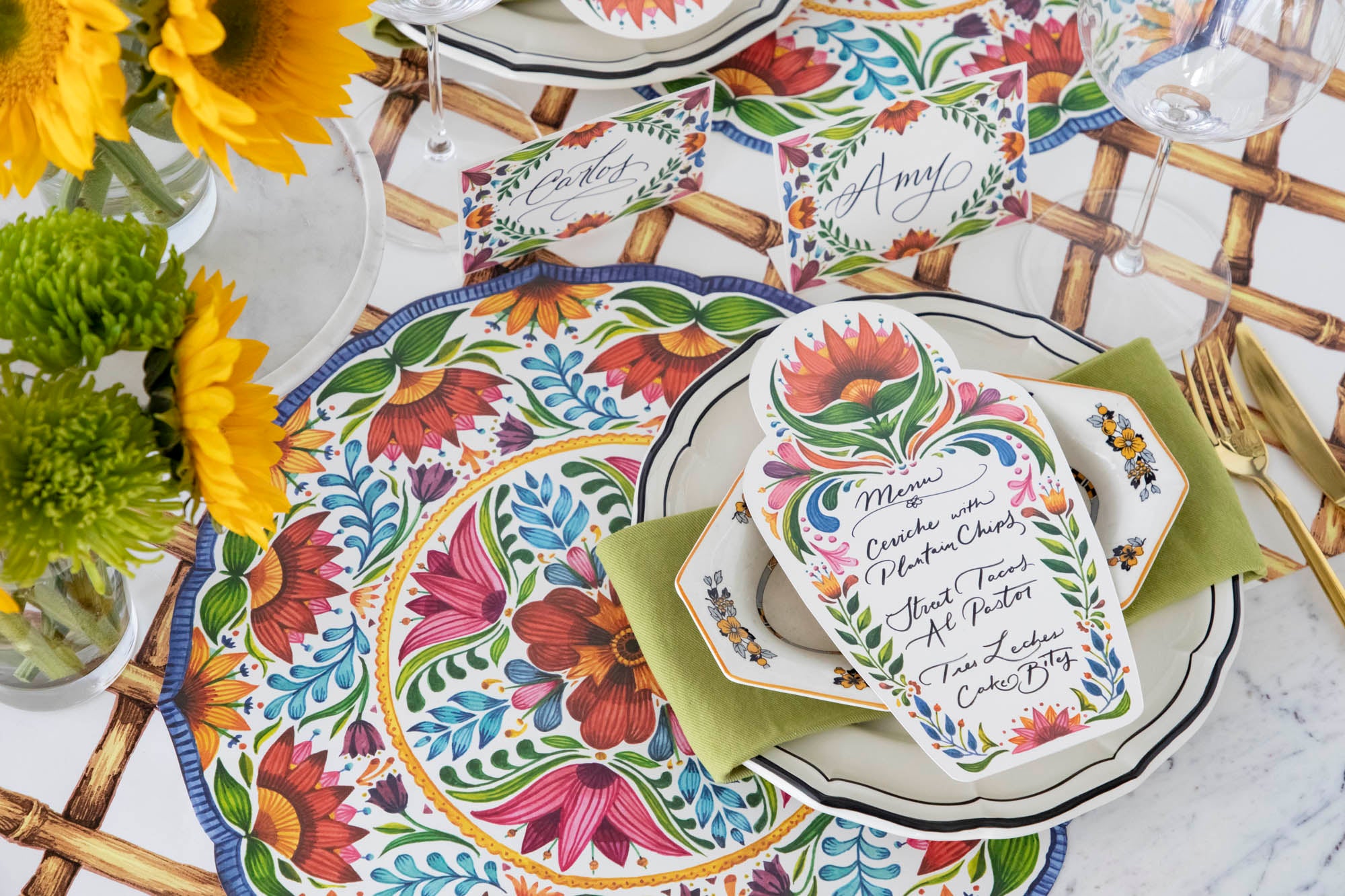 A vibrant place setting featuring a Fiesta Floral Table Card with a menu written on it in beautiful script resting on the plate.