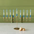 Gold menorah with blue and white menorah candles next to a dreidel against a green wall.