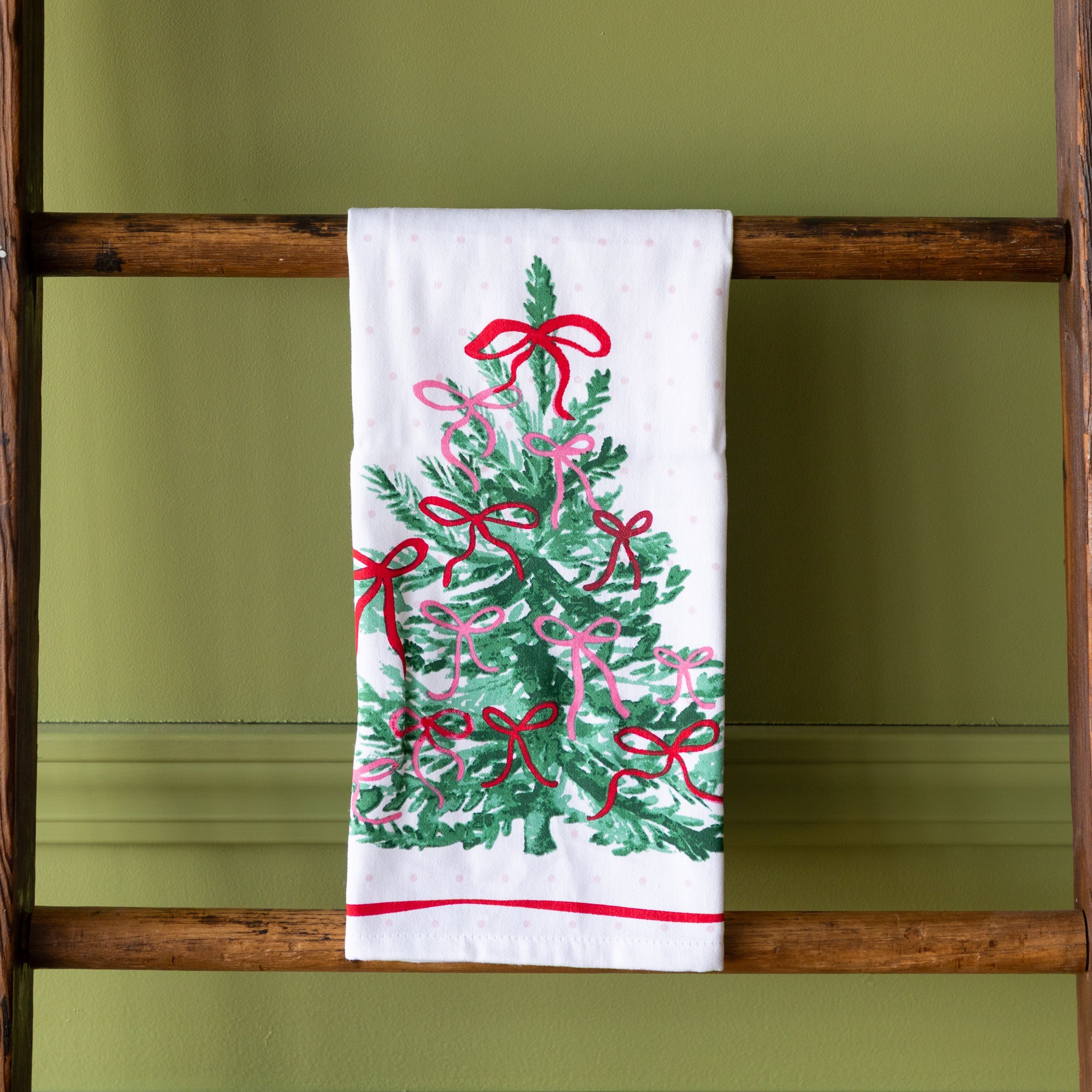 Very Merry Dishtowel hung on a wooden ladder.
