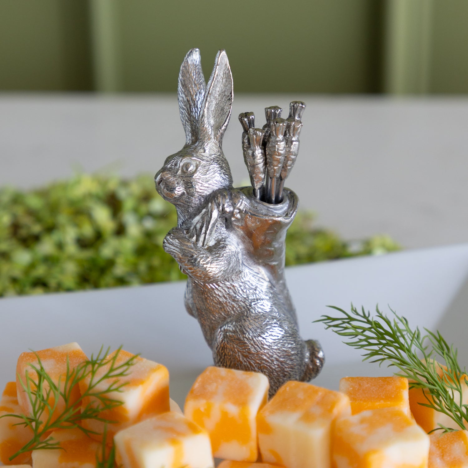 Silver rabbit carrying carrot picks on a platter with cheese cubes.