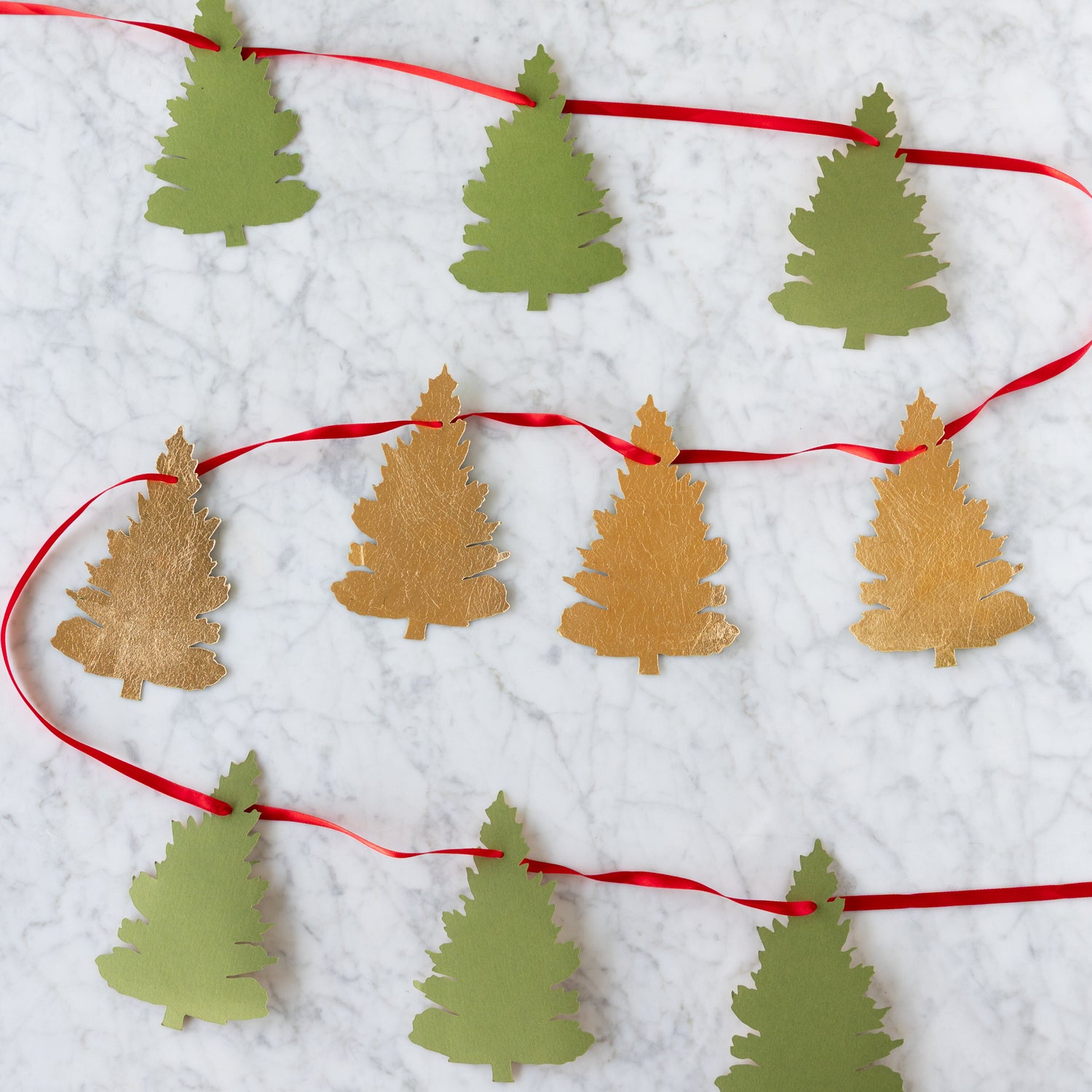 Decorative string with paper Christmas tree cutouts on a white background.