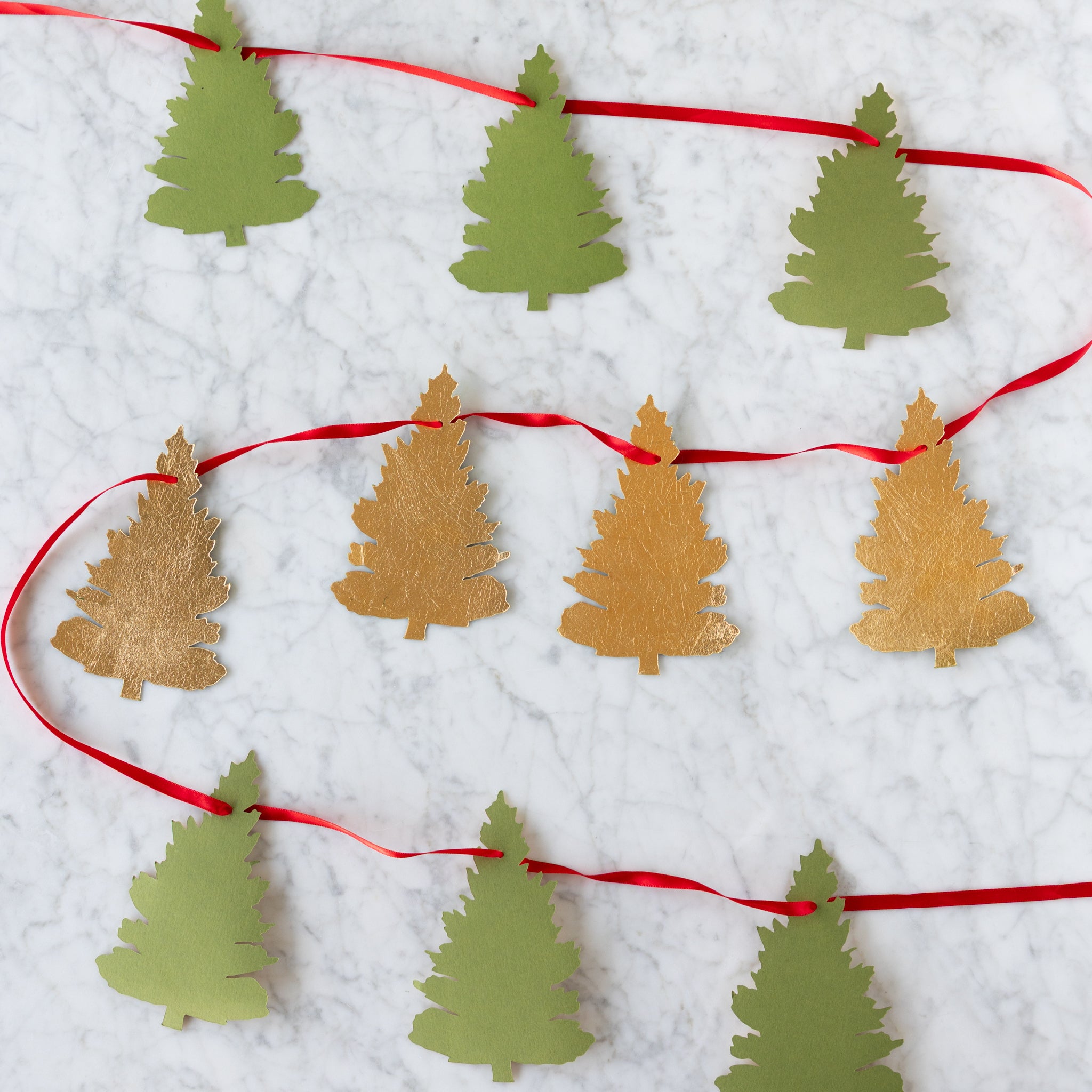 Decorative string with paper Christmas tree cutouts on a white background.