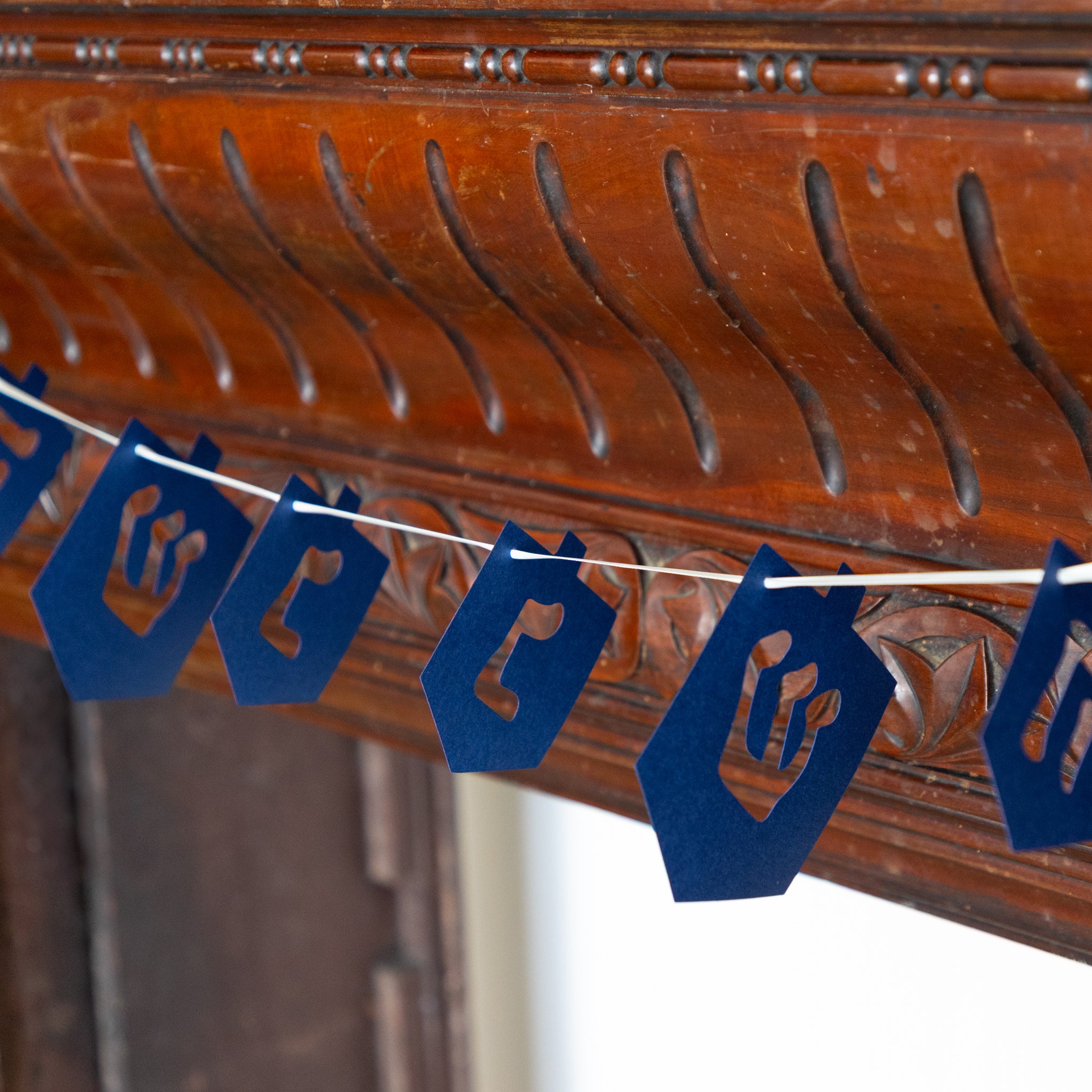 Blue paper cutout decorations on a string against a wooden background. 