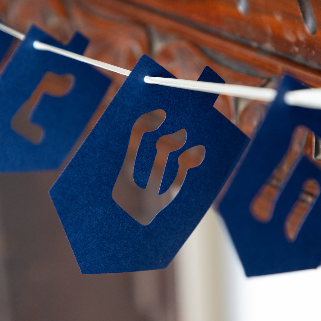 Dreidel shaped garland in blue hanging on a mantle. 