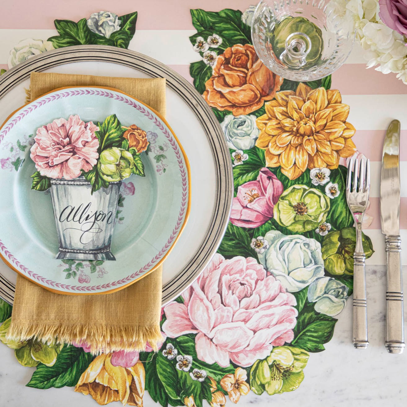 A table setting with plates, silverware, and a Die-cut Derby Wreath Placemat by Hester &amp; Cook.