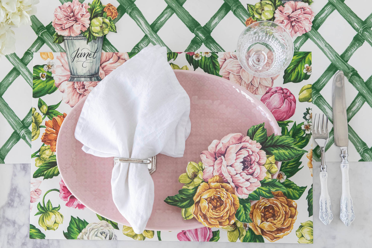 A pink placemat adorned with a floral swag and utensils, serving as a charming Hester &amp; Cook Garden Derby Table Accent.