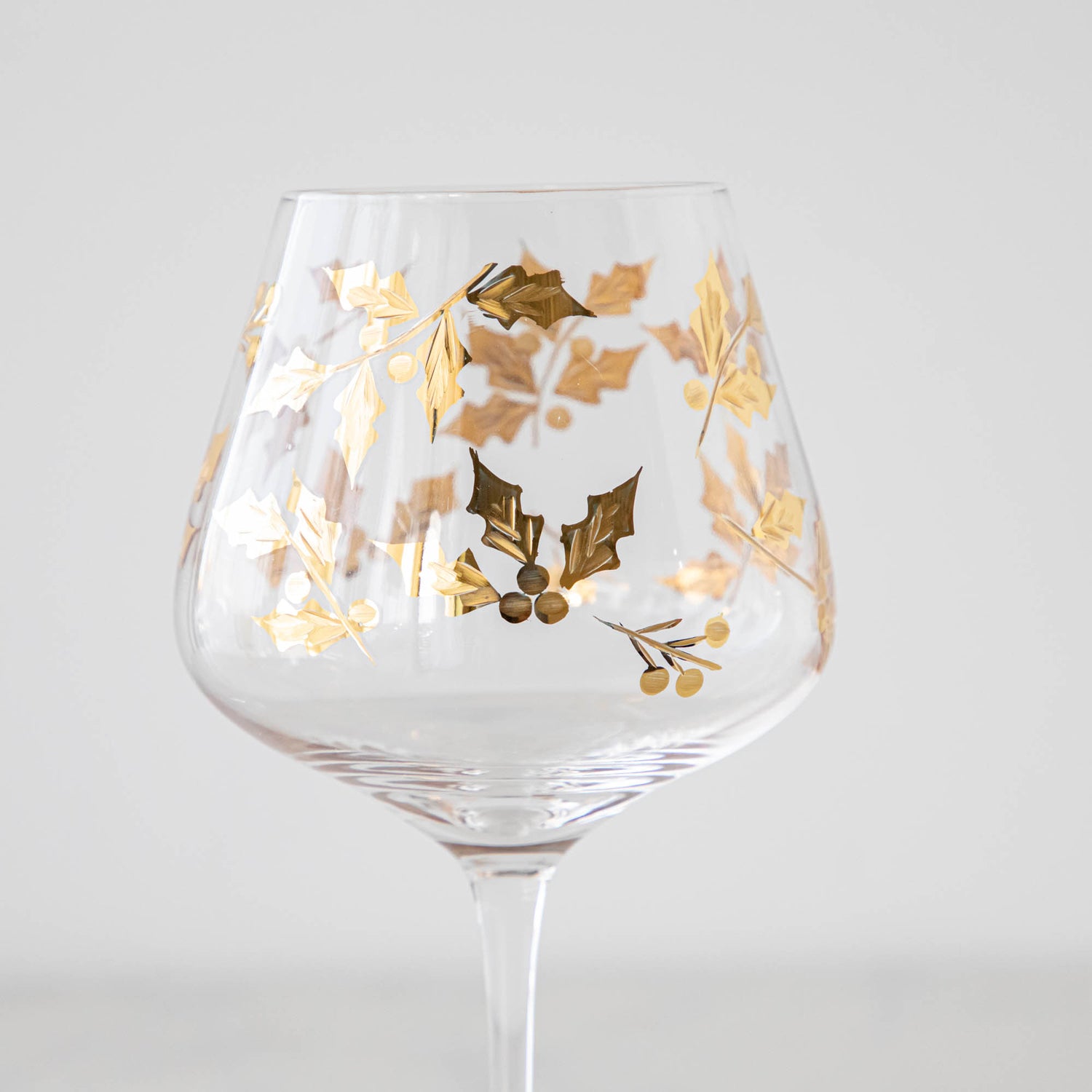 A close up view of Gold Holly Etched Goblet showing its 24 karat gold holly etched details on the glass.