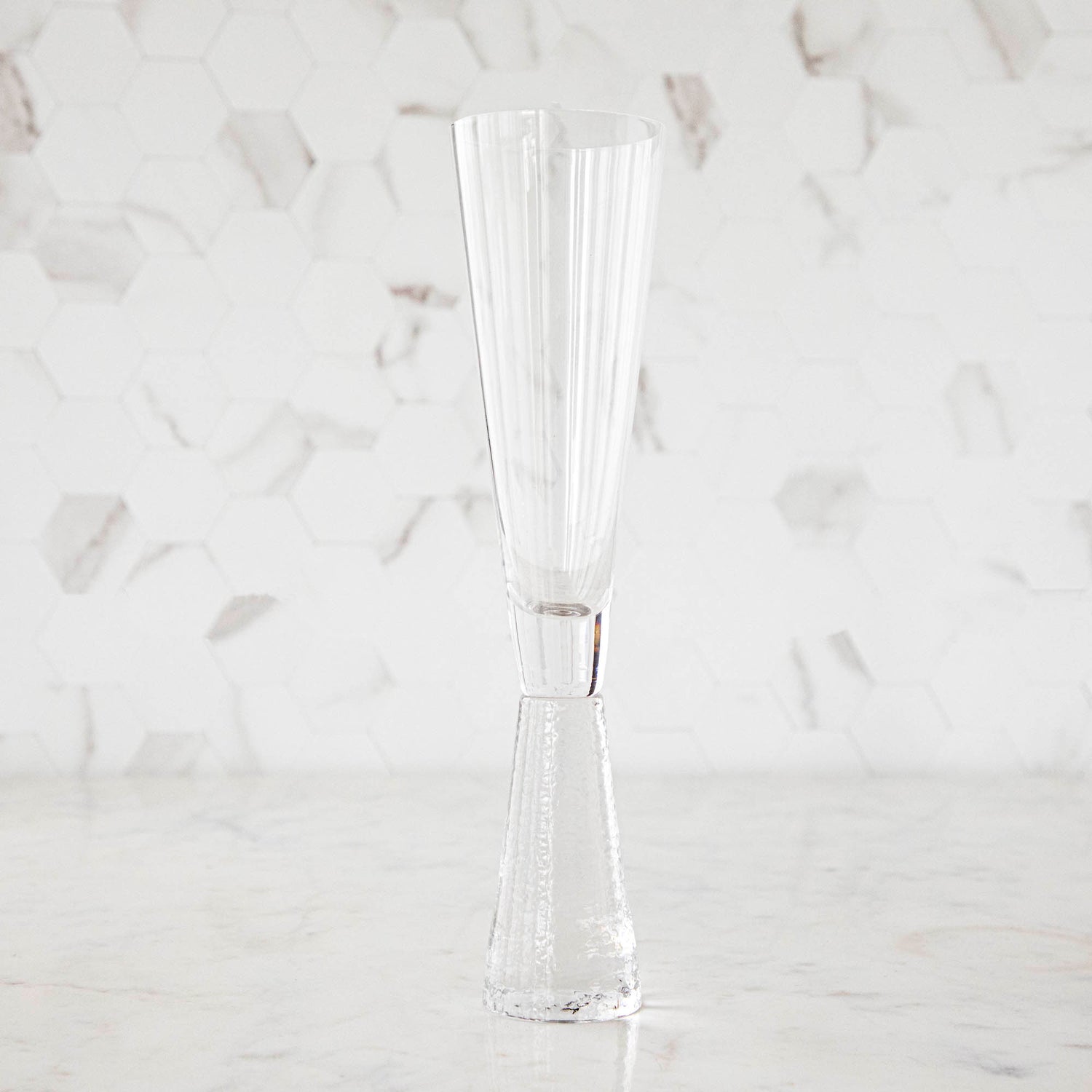 A clear Livogno Hammered Stem Glassware Champagne Flute on a white surface by Zodax.