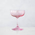 A pink crystal stemware wine glass on a marble table.