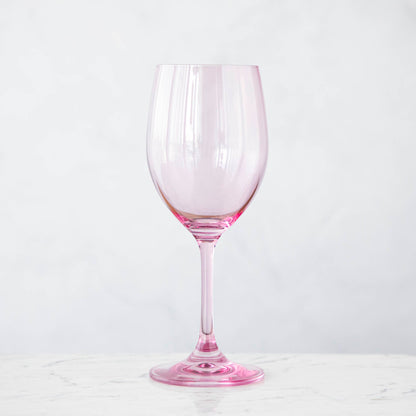 A pink crystal stemware wine glass on a marble table.