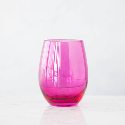 A pink crystal stemware wine glass on a marble table.