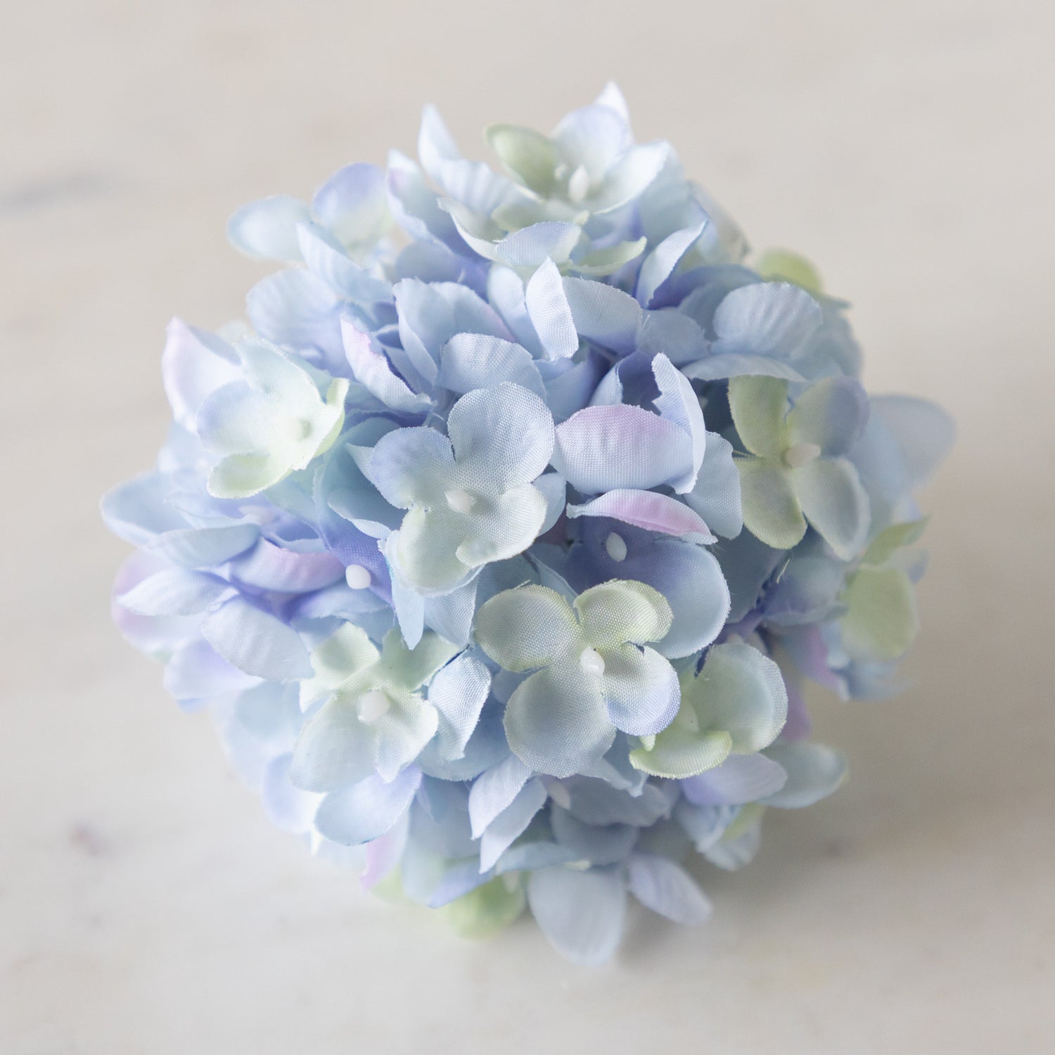 Pastel blue and green flower Hydrangea Napkin Ring on a marble surface.