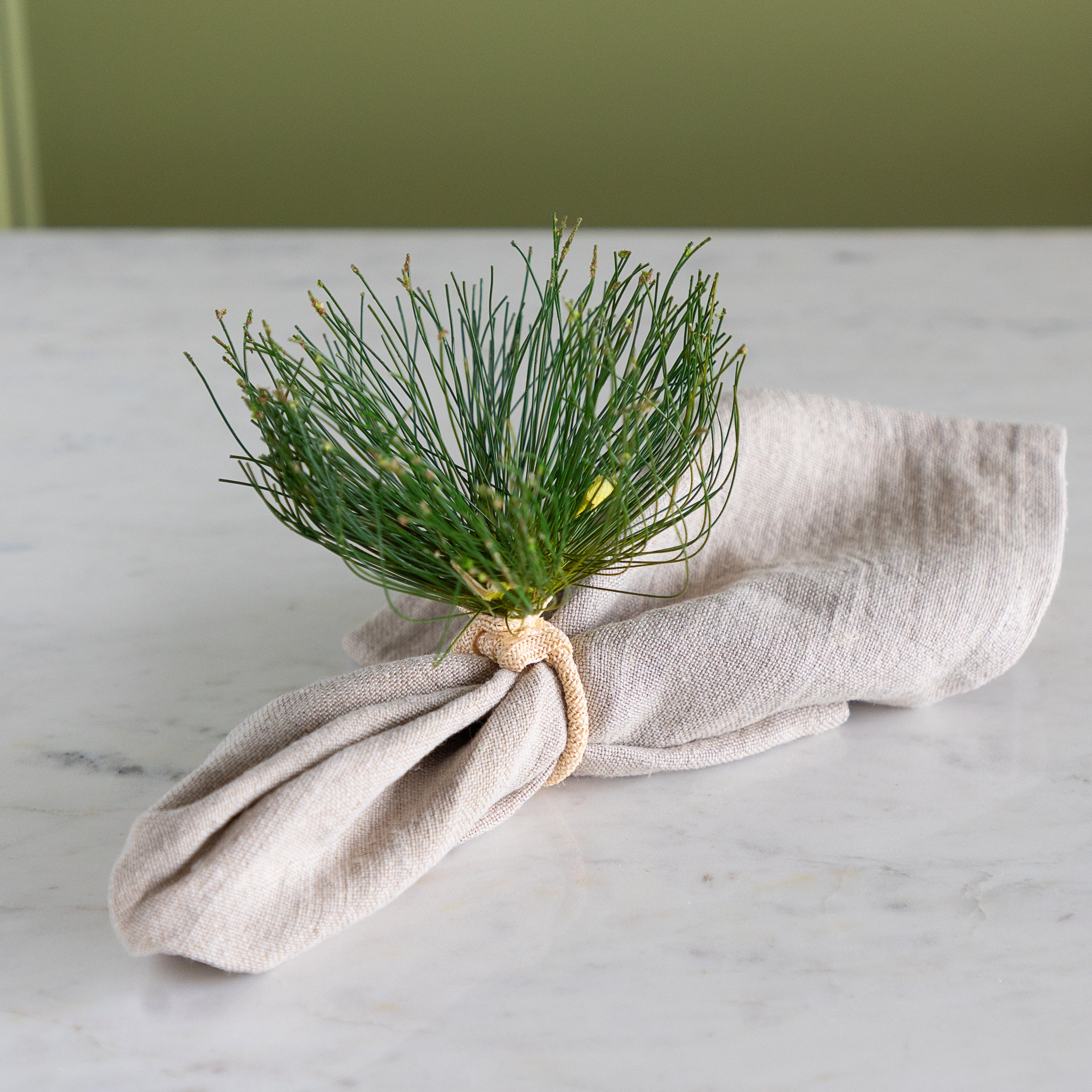 Cypress Bloom Napkin Ring with a beige napkin on a marble table.