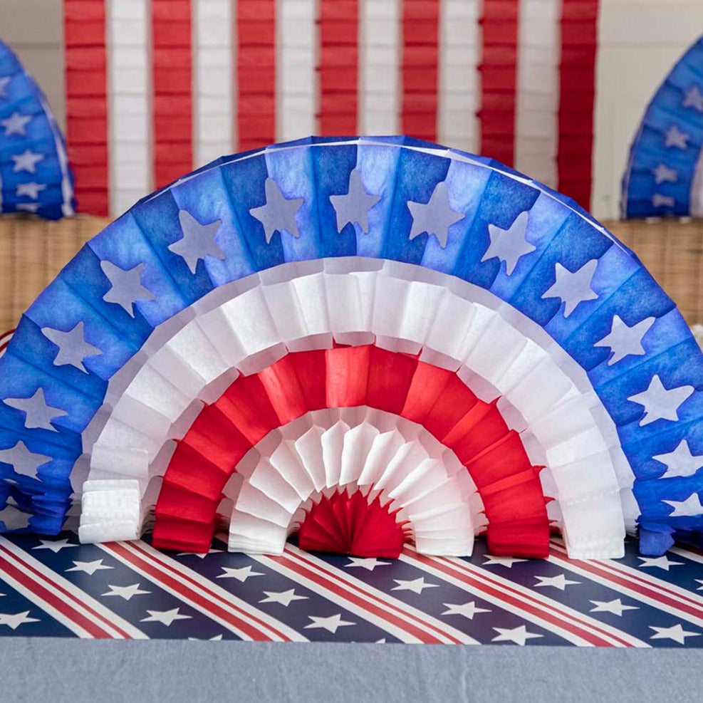 A patriotic party table set up with red, white, and blue Hester &amp; Cook Patriotic Star Fan decorations.