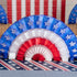 A patriotic party table set up with red, white, and blue Hester & Cook Patriotic Star Fan decorations.
