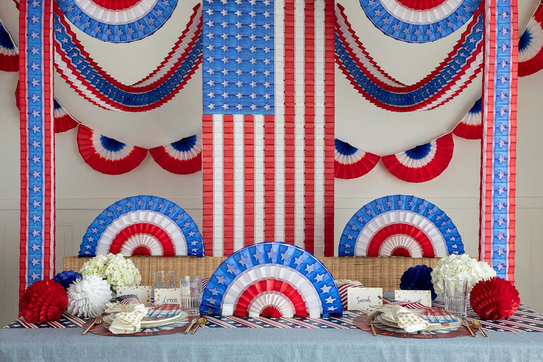A patriotic party table set up with red, white, and blue Hester &amp; Cook Patriotic Star Fan decorations.