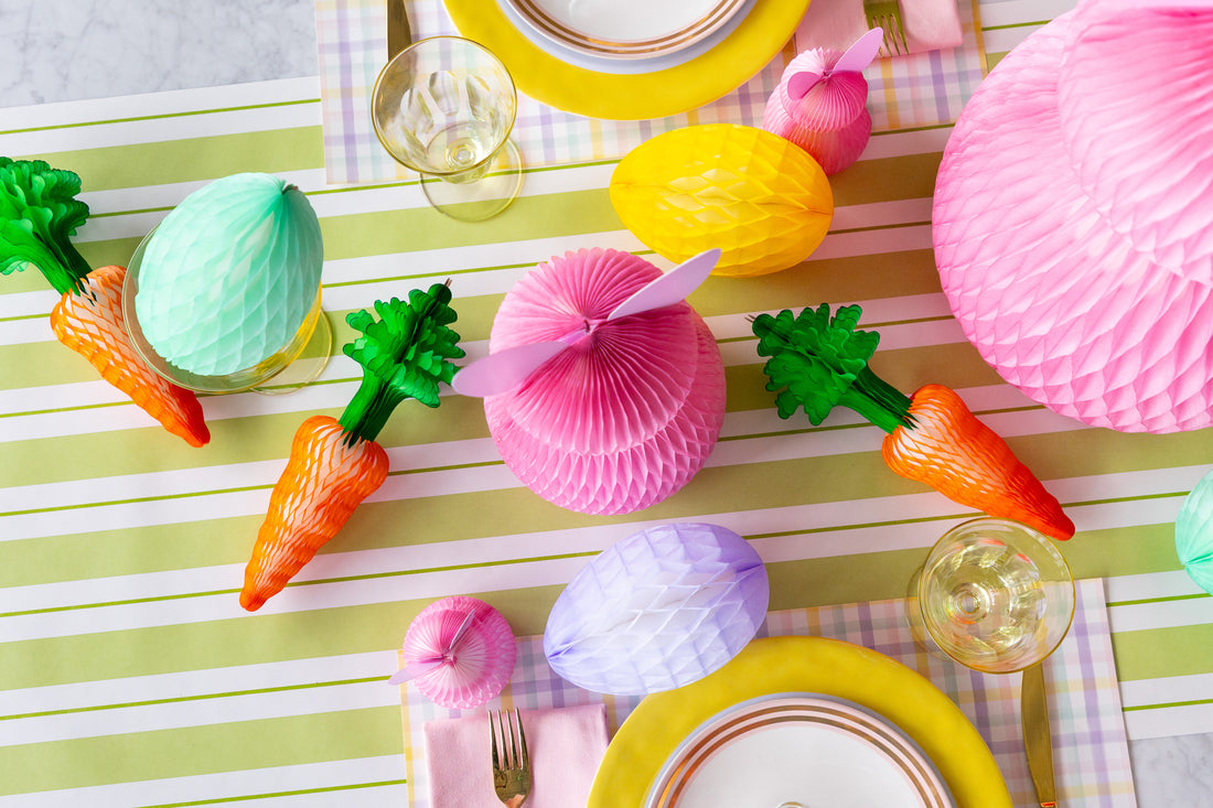 Colorful Easter table setting with decorative eggs, carrots, and bunny ears on a striped table runner.