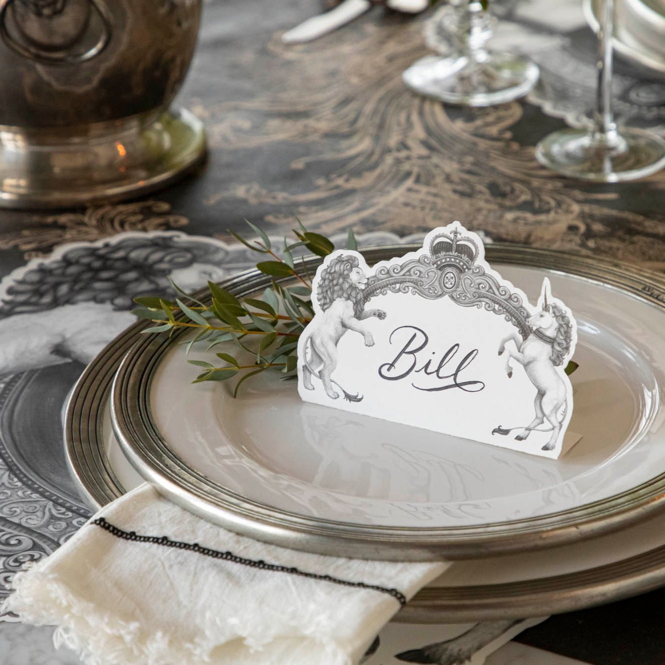 Regal Crest Place Card with &quot;Bill&quot; written on it, resting on dinner plates, on a table setting for one.