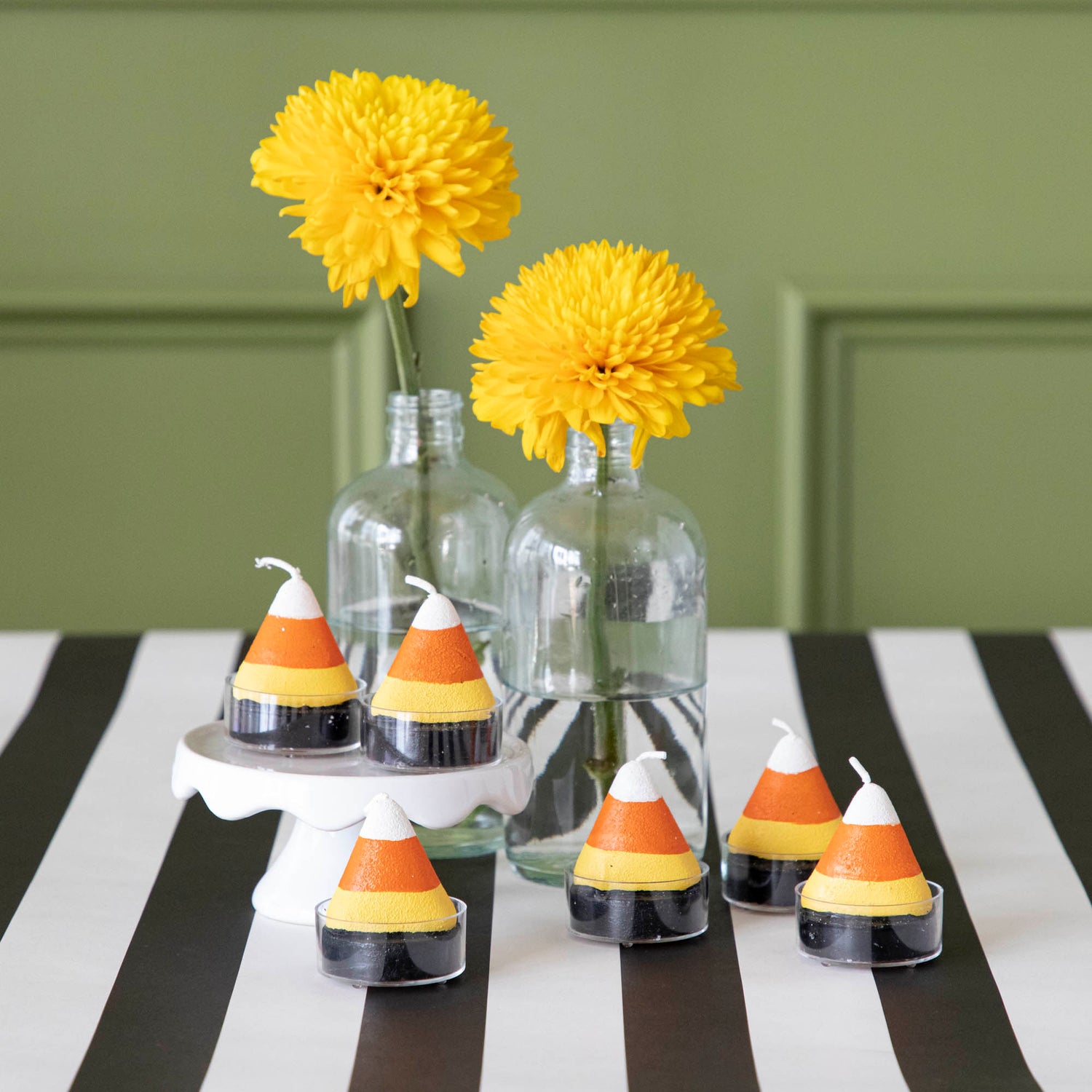 Candy corn themed tea light candles with flowers on a black stripe runner.