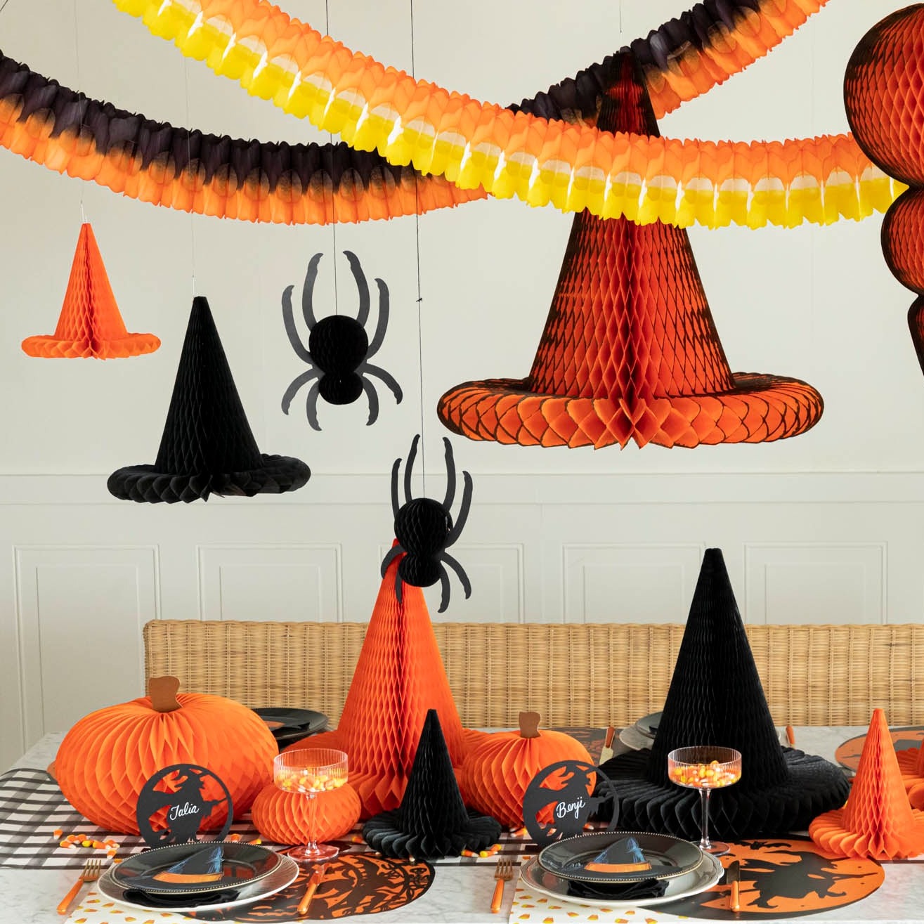 Hanging orange, black &amp; yellow various honeycomb overtop of a Halloween themed table with more Halloween honeycomb.