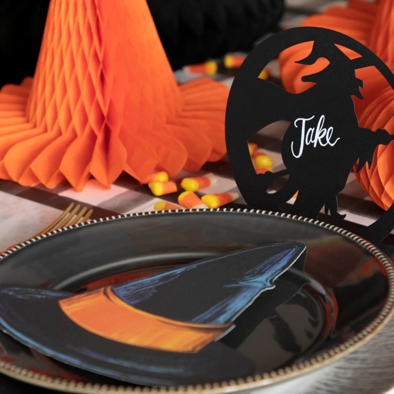 A die-cut black witch hat with an orange band, on a Halloween themed tablescape.