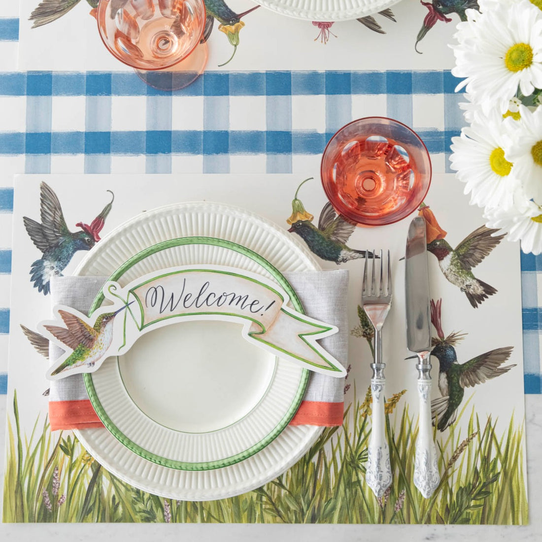 An elegant tablescape with Hummingbirds Placemats by Hester &amp; Cook, accentuated by paper placemats for an added touch of sophistication.
