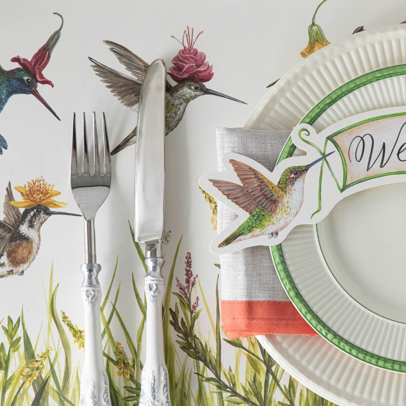 Close-up of the Hummingbirds Placemat under a place setting, showing hummingbirds with flower hats in detail.