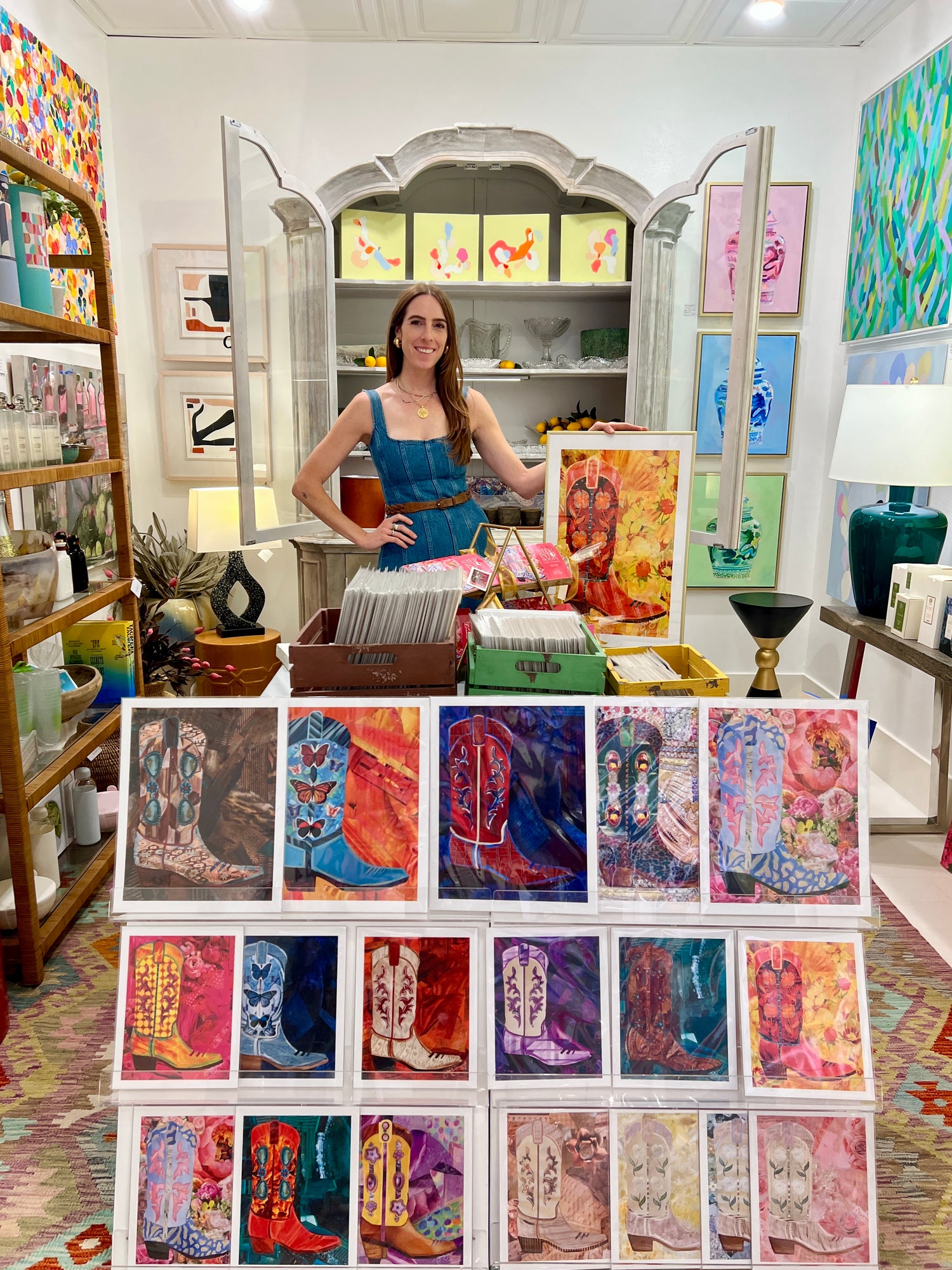 Woman standing behind a display of colorful art prints in an art store.
