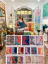 Woman standing behind a display of colorful art prints in an art store.