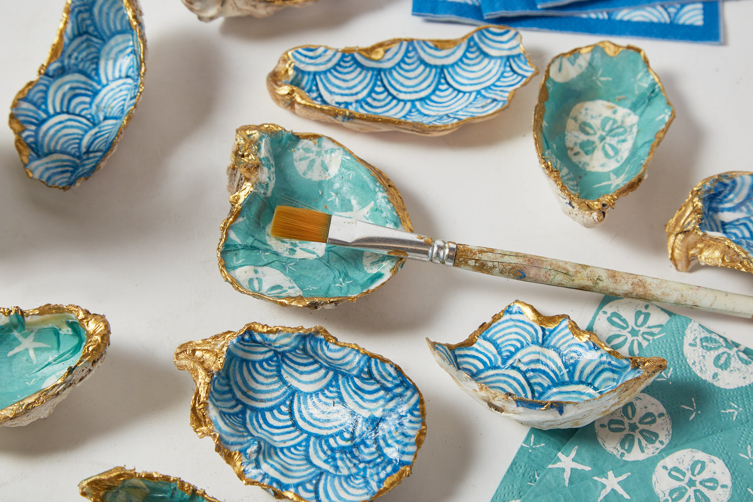 Decorative oyster shells with blue and white patterns on a white surface.