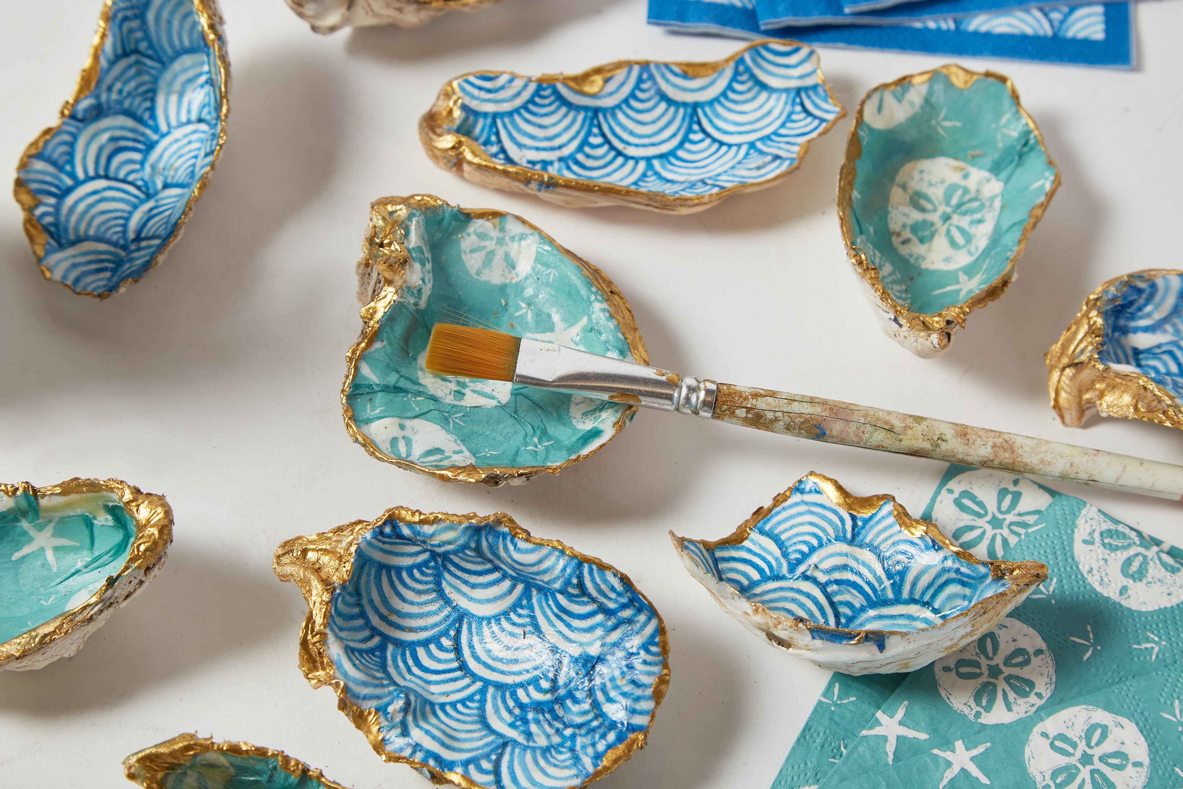 Decorative oyster shells with blue and white patterns on a white surface.